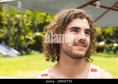Junger Kaukasier mit lockigen Haaren lächelt draußen Stockfoto