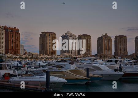 Porto Arabia Marina in der Perle, Doha, Katar mit luxuriösen Yachten und Booten, die am Yachthafen mit Wohngebäuden im Hintergrund angedockt sind. Stockfoto