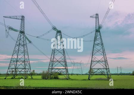 Gruppensilhouette von Sendetürmen, Strommast, Strommast, Stahlgitterturm in der Dämmerung. Struktur Hochspannungssäule, Überkopfleistung Stockfoto