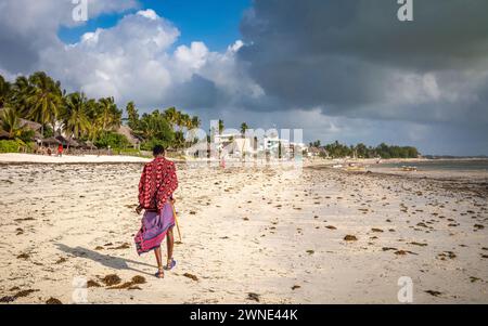 Ein junger Maasai-Krieger in einem traditionellen shuka spaziert am Jambiani Beach, Sansibar, Tansania Stockfoto