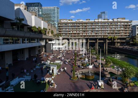 Die Leute sitzen auf der Seeterrasse vor dem Barbican Centre. Das Barbican Centre ist ein renommiertes Kunstzentrum und Teil des Barbican Estate, Stockfoto