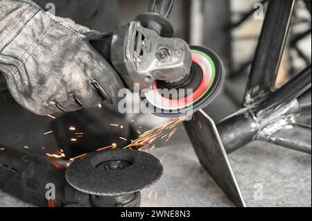 Funken vom Winkelschleifer. Mann bei der Arbeit. Industriearbeiter auf der Baustelle. Stahlverarbeitung. Funken fliegen aus der elektrischen Schleifmaschine, Nahaufnahme. Stockfoto