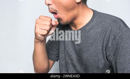 Gutaussehender asiatischer Mann mit weißem T-Shirt auf isoliertem Hintergrund, der schmerzhaften Hals, Halsschmerzen für Grippe, Klumpen und Infektion berührt. Stockfoto