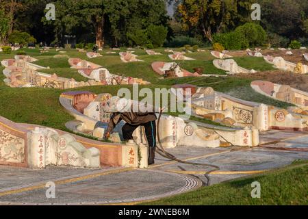 Arbeiter, der sich um Grabsteine auf dem chinesischen Friedhof in Chiang Mai, Thailand kümmert Stockfoto