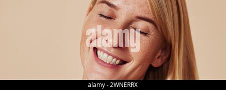 Porträt einer jungen glücklichen Frau, die ihren Kopf auf die Seite kippt. Close-up-Studio-Aufnahme einer glücklichen Frau mit Sommersprossen, die mit geschlossenen Augen lächelt. Stockfoto