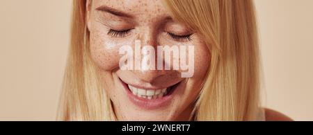 Zugeschnittene, detailreiche Aufnahme positiver Frauen mit Sommersprossen. Close-up-Porträt einer jungen Frau mit geschlossenen Augen und Sommerhaut über pastellfarbenem Backdro Stockfoto