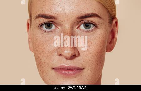 Close-up-Studio-Aufnahme einer jungen Frau mit Sommersprossen. Porträt einer natürlichen Schönheit Frau mit glatter Haut vor pastellfarbenem Hintergrund. Stockfoto