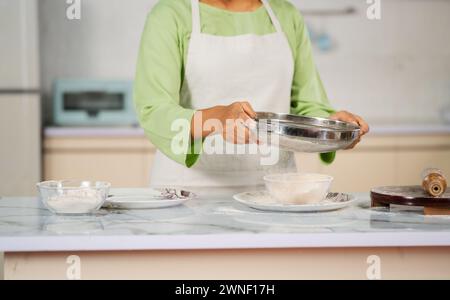 Nahaufnahme der indischen Frau, die Mehl für die Herstellung von Chapati in der Küche vorbereitet - Konzept der hausgemachten Nahrung, gesunde Ernährung und Lebensmittelzubereitung Stockfoto