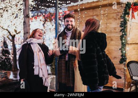 Drei junge Erwachsene verbringen eine helle Nacht im Hintergrund mit glitzernden Lichtern und festlichen Dekorationen und teilen Glück. Stockfoto