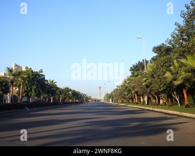 Kairo, Ägypten, 16. Dezember 2023: New Cairo City Street mit Grünflächen auf beiden Seiten von Gehwegen, Gras, Bäumen und Palmen, New Cairo ist ein Satell Stockfoto