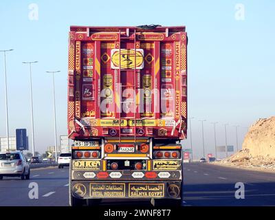 Kairo, Ägypten, 16. Dezember 2023: Tieflader-Lkw-Großfahrzeug mit einem Stahlcontainer, in Kairo Suez spezifische Spur, Versand- und Lieferservice Stockfoto