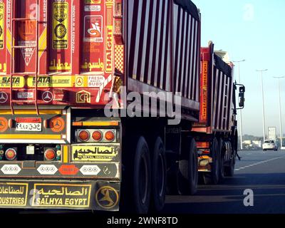 Kairo, Ägypten, 16. Dezember 2023: Tieflader-Lkw-Großfahrzeug mit einem Stahlcontainer, in Kairo Suez spezifische Spur, Versand- und Lieferservice Stockfoto