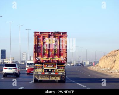 Kairo, Ägypten, 16. Dezember 2023: Tieflader-Lkw-Großfahrzeug mit einem Stahlcontainer, in Kairo Suez spezifische Spur, Versand- und Lieferservice Stockfoto