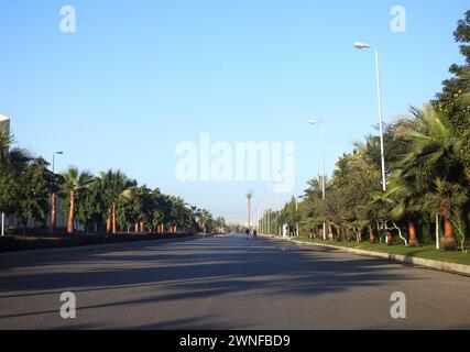 Kairo, Ägypten, 16. Dezember 2023: New Cairo City Street mit Grünflächen auf beiden Seiten von Gehwegen, Gras, Bäumen und Palmen, New Cairo ist ein Satell Stockfoto