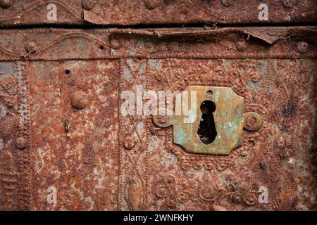 Eine Nahaufnahme einer alten rostigen, verzierten Metallkiste mit Schlüssellochplatte Stockfoto