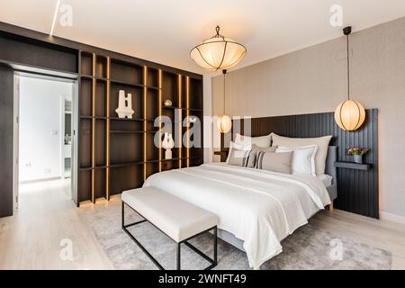 Ein Hauptschlafzimmer mit einem großen Bett, umgeben von schwarzen Regalen in luxuriösen mediterranen Immobilien Stockfoto
