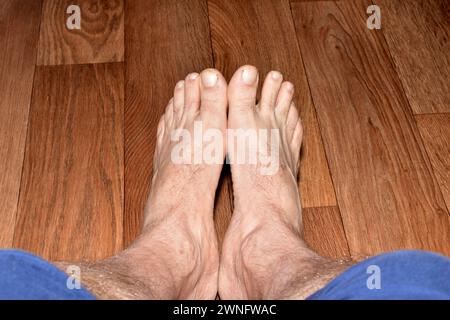 Blick von oben auf männliche Beine, die Füße sind miteinander verbunden und stehen auf dem Boden. Stockfoto