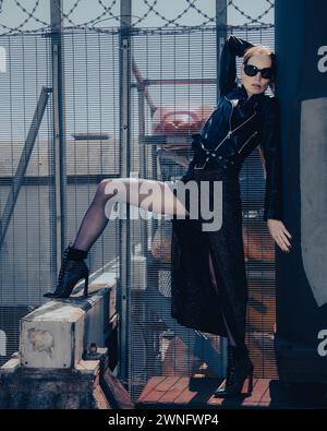 Eingezäunt posiert ein Modemodell gegen einen Zaun Stockfoto