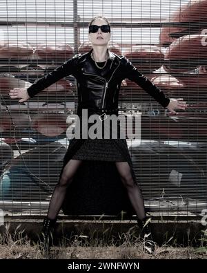 Eingezäunt posiert ein Modemodell gegen einen Zaun Stockfoto