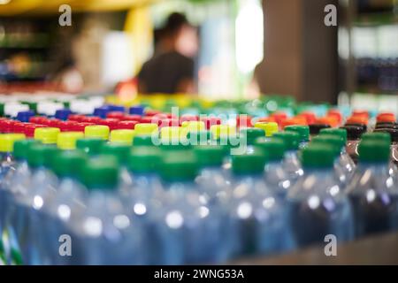Viele blaue halbstündige Mineralwasser-Flaschen aus Kunststoff mit kleinem Volumen, grüner gelber roter Verschluss im Lager. Hoher Kunststoffverbrauch im Alltag, was für eine Umfrage Stockfoto
