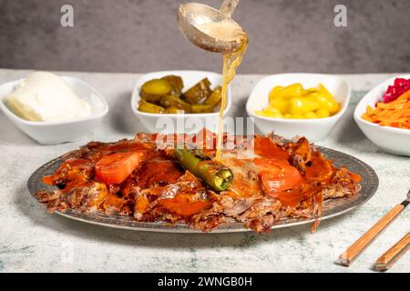 iskender Kebab. Traditionelle türkische Küche mit Tomatensauce und Butter. iskender Döner auf grauem Hintergrund Stockfoto