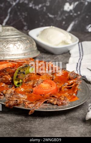 iskender Kebab. Traditionelle türkische Küche mit Tomatensauce und Butter. iskender Döner auf dunklem Hintergrund Stockfoto