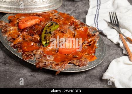 iskender Kebab. Traditionelle türkische Küche mit Tomatensauce und Butter. iskender Döner auf dunklem Hintergrund Stockfoto