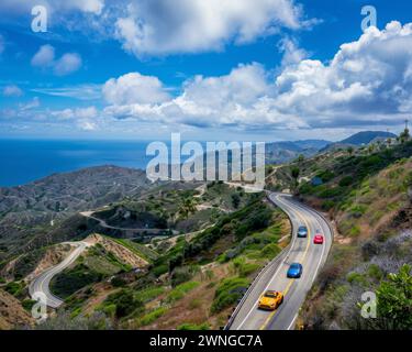 Drei Autos fahren eine gewundene Bergstraße hinunter, wobei das Meer im Hintergrund sichtbar ist. Stockfoto