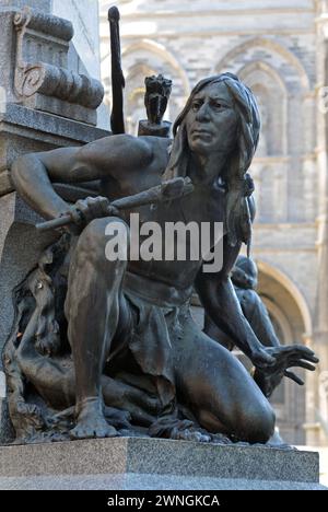 Eine Skulptur eines Irokesen-Kriegers vom Bildhauer Louis-Philippe Hébert am Fuß des Maisonneuve-Monuments in Old Montreal's Place d'Armes. Stockfoto