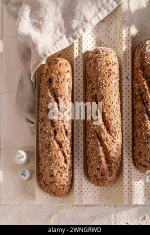 Leckere Vollkorn-Baguettes, die in Sesam und Leinsamen gebacken werden. Vollkornbaguettes auf dem Land. Stockfoto