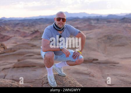 Ein brutaler Mann mittleren Alters bei Sonnenuntergang in der Wüste Stockfoto