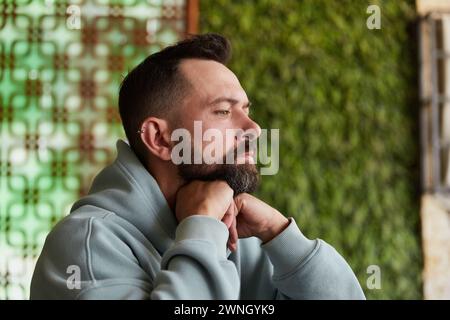 Junger erwachsener Mann mit den Händen im Kopf, der im Café sitzt. Problembegriff, Stressgedanken, Schwierigkeit und Krise Stockfoto