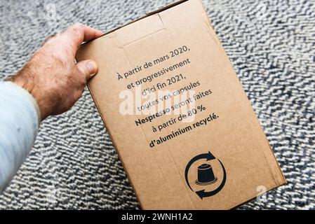 Bremen, Deutschland 10. Dezember 2023: POV Eine männliche Hand liest auf dem Karton, dass von März 2020 bis 2021 alle Nespresso Kapseln der Schweizer Marke aus 80 Prozent Aluminium hergestellt werden, um Nachhaltigkeit zu gewährleisten Stockfoto