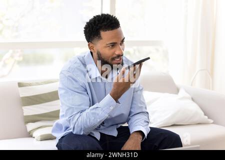 Ernster junger schwarzer Geschäftsmann, der das Smartphone im Mund hält Stockfoto
