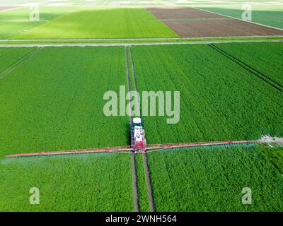 Luftaufnahme einer Maschine, die chemische Zusätze auf Feldfrüchte in einem landwirtschaftlichen Feld sprüht Stockfoto