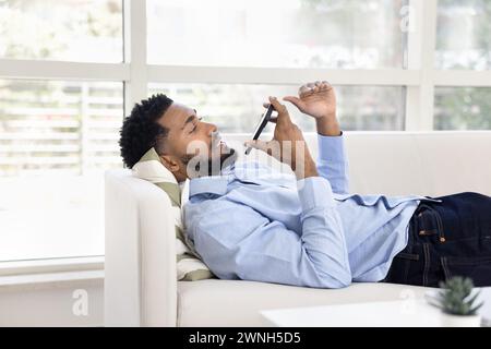 Ernsthafter afrikanischer Geschäftsmann, der über Lautsprecher auf dem Handy spricht Stockfoto