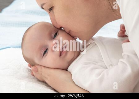 Mutter küsst die Nase ihres Babys auf einem Bett Stockfoto