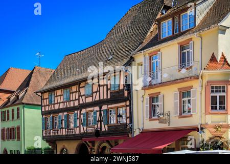 Verzierte traditionelle Fachwerkhäuser mit blühenden Blumen in einem beliebten Dorf an der elsässischen Weinstraße in Kaysersberg, Frankreich Stockfoto