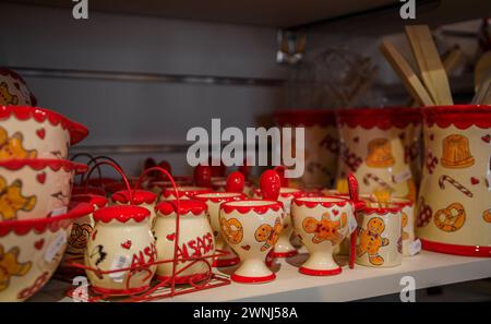 Kaysersberg, Frankreich - 2. Juni 2023: Keramikbecher mit traditionellen elsässischen Motiven, Lebkuchenmann und Brezeln in einem Souvenirladen Stockfoto