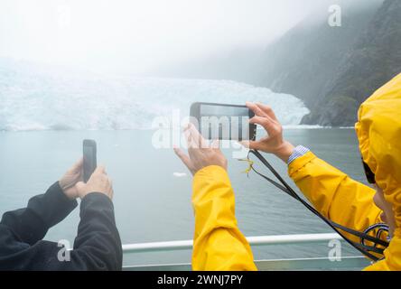 Touristen machen Fotos vom Holgate-Gletscher mit Smartphones im Regen. Kenai Fjords National Park. Seward. Alaska. Stockfoto