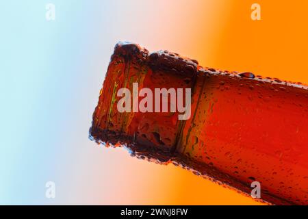 Der Hals einer transparenten Glasflasche ist mit großen Tropfen bedeckt. Nahaufnahme auf einem verlaufenen Hintergrund. Stockfoto