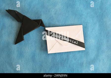 Origami aus schwarzem Rabenpapier mit weißem Briefumschlag mit vertraulichem Wort. Konzept für vertrauliche Nachrichten. Stockfoto