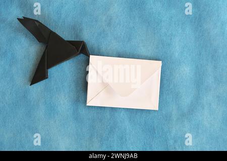 Origami aus schwarzem Rabenpapier mit weißem Briefumschlag. E-Mail, Nachricht, Kurier und Briefversand. Stockfoto