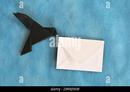 Origami aus schwarzem Rabenpapier mit weißem Briefumschlag. E-Mail, Nachricht, Kurier und Briefversand. Stockfoto