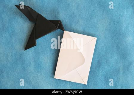 Origami aus schwarzem Rabenpapier mit weißem Briefumschlag. E-Mail, Nachricht, Kurier und Briefversand. Stockfoto