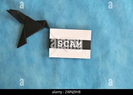 Origami aus schwarzem Rabenpapier mit weißem Briefumschlag mit Wortbetrug. Konzept für Betrugsmeldungen. Stockfoto