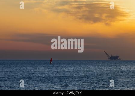 Gehen Sie an Bord mit Segel und Gasplattform im Meer bei Sonnenuntergang in Nachsholim Israel Stockfoto