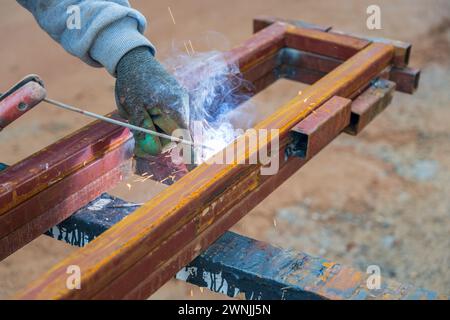 Schweißer schweißen an einem sonnigen Tag zwei Eisenprofile auf der Baustelle Stockfoto