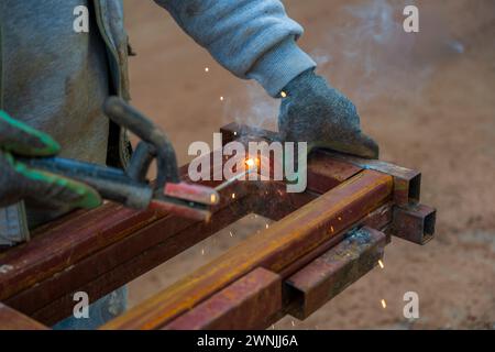 Schweißer schweißen an einem sonnigen Tag zwei Eisenprofile auf der Baustelle Stockfoto