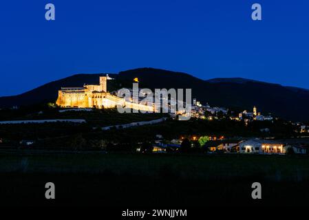 Blick auf die beleuchtete Altstadt von Assisi mit dem Kloster und der Basilika St. Franziskus und St. Klara bei Nacht, Umbrien, Italien Stockfoto